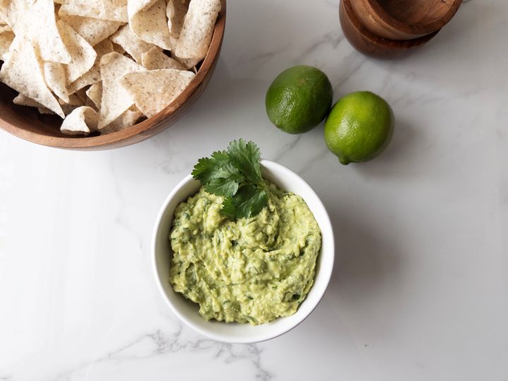 Creamy guacamole dip with chips, bowls and limes