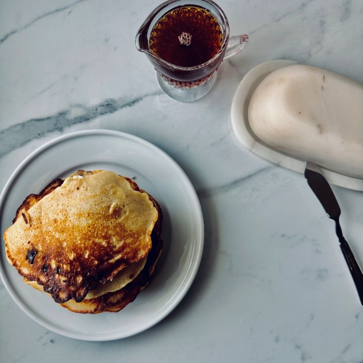 Plate of Fresh Milled Flour Pancakes with syrup and a butter dish on the side.