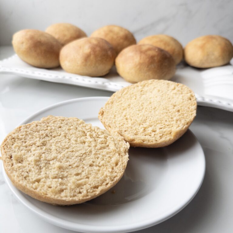 Fresh Milled Hamburger Buns sitting on a plate with a serving dish of buns in the background