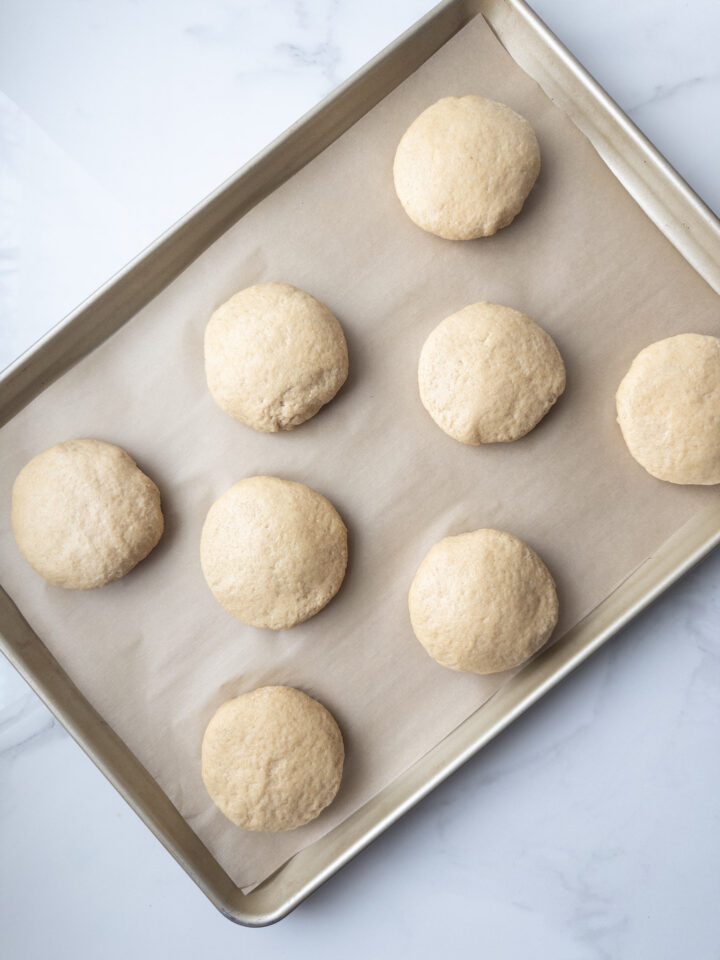 Prepared baking sheet with 8 buns before the second rise