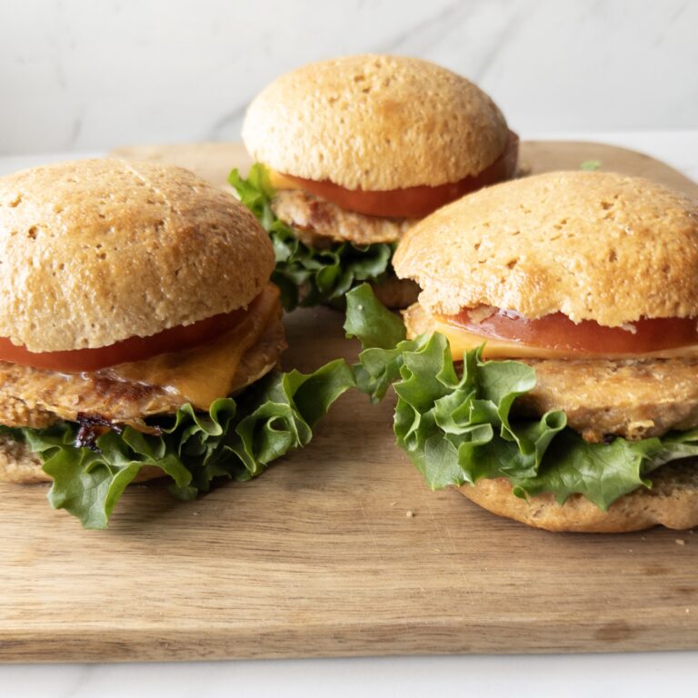 Three assembled Gluten-Free Turkey Burgers sitting on a cutting board