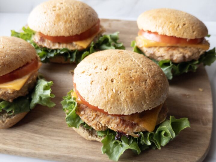 Four assembled Gluten-Free Turkey Burgers sitting on a cutting board