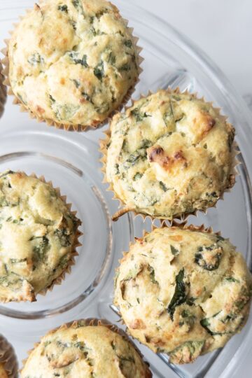 Savory Gluten-Free Spinach Feta Muffins sitting on a glass cake plate