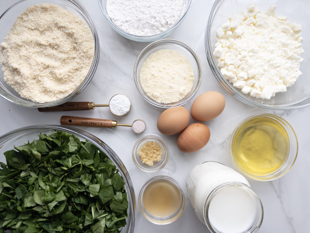 Ingredients to make Savory Gluten Free Spinach Feta Muffins spread out on a counter