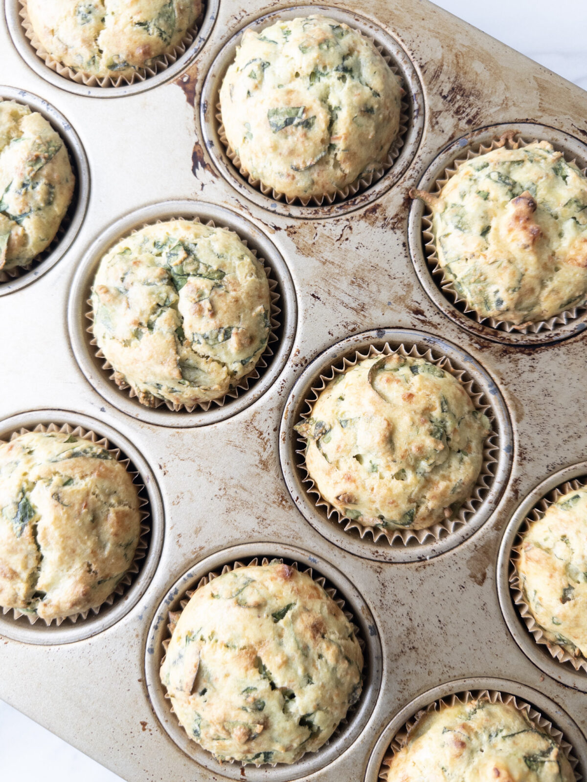 Muffin tin with baked Savory Gluten-Free Spinach Feta Muffins out of the oven