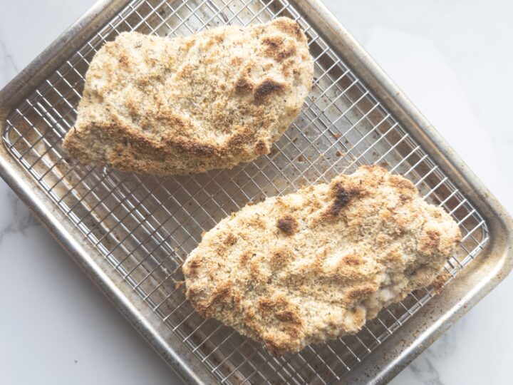 2 cooked chicken breasts sitting on a wire lined baking sheet