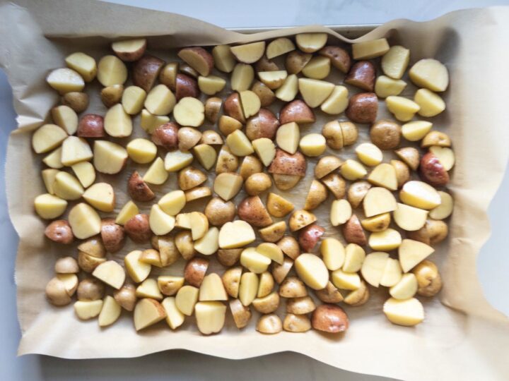 Baby potatoes cut, tossed, and ready to be placed in the oven