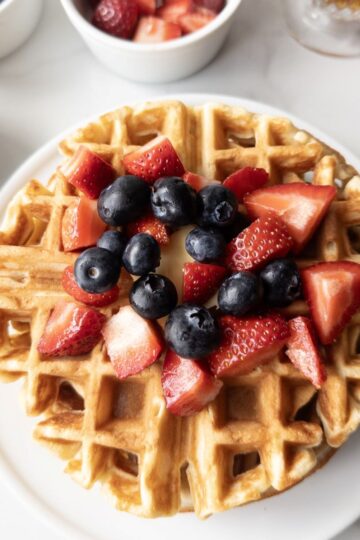 Fresh Milled Waffles with Greek Yogurt with berries on top and toppings in the background