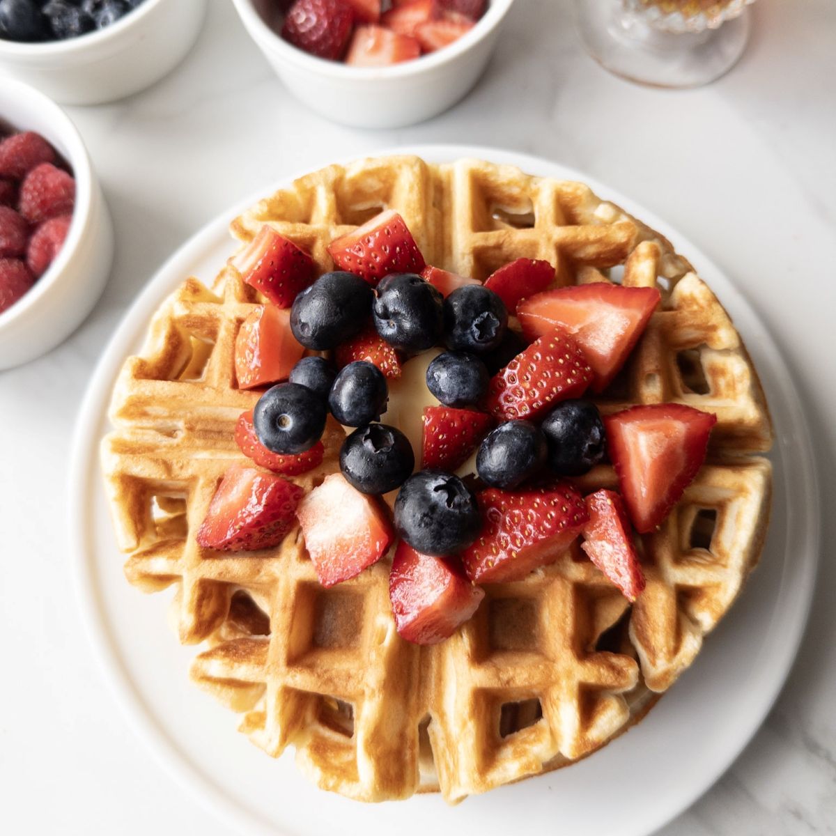 Fresh Milled Waffles with Greek Yogurt with berries on top and toppings in the background