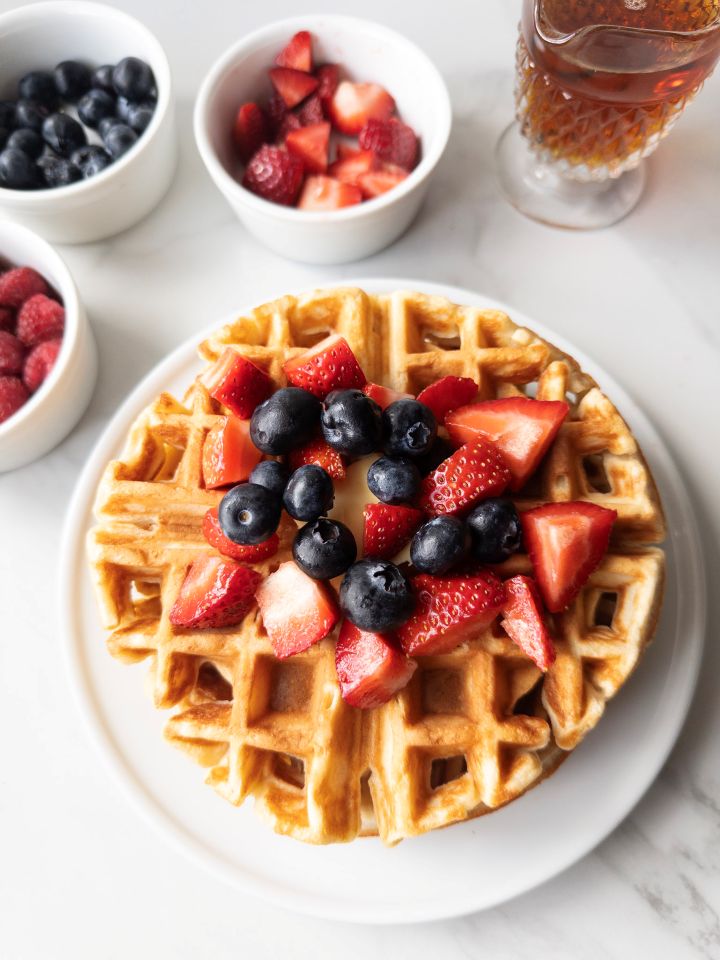 Fresh Milled Waffles with Greek Yogurt with berries on top and toppings in the background