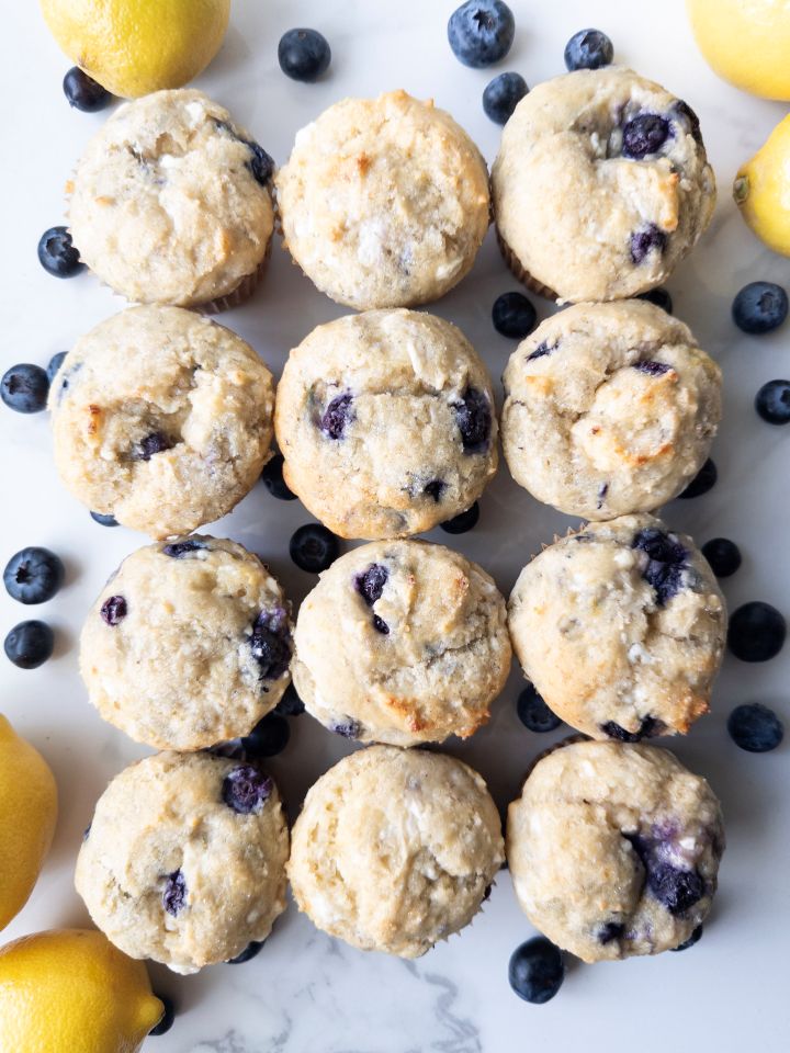 Lemon Blueberry Cottage Cheese Muffins (Gluten-Free) on the counter with blueberries and lemons