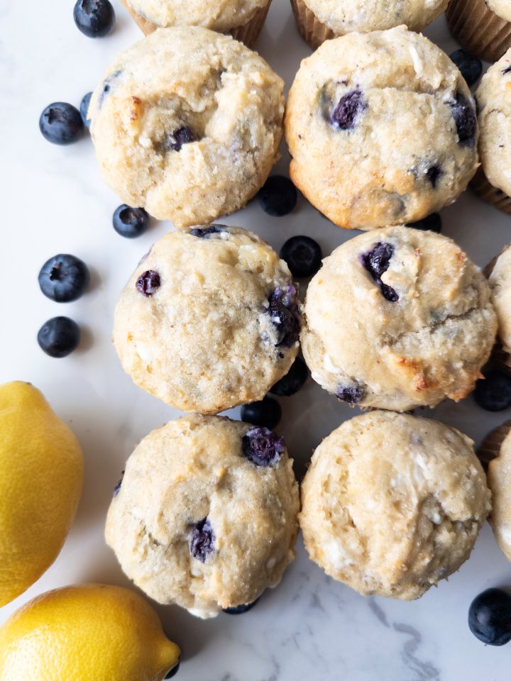 Lemon Blueberry Cottage Cheese Muffins (Gluten-Free) on the counter with blueberries and lemons