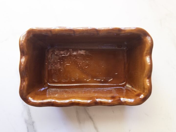 Empty ceramic loaf pan greased and ready for pumpkin bread batter