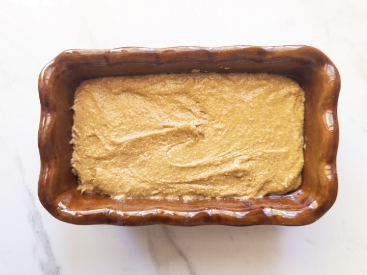 Pumpkin bread batter poured into a greased ceramic loaf pan, ready to bake