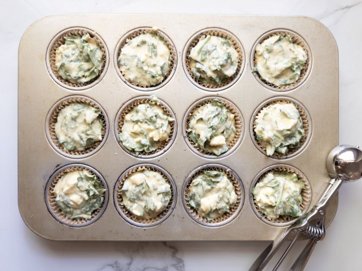 Spinach feta muffin batter scooped into a 12-cup muffin tin before baking