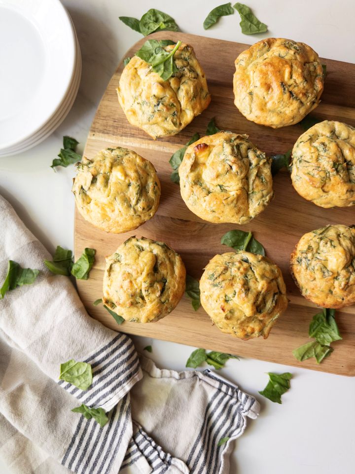 Savory spinach and feta muffins with fresh milled flour arranged on a wooden board with a linen napkin