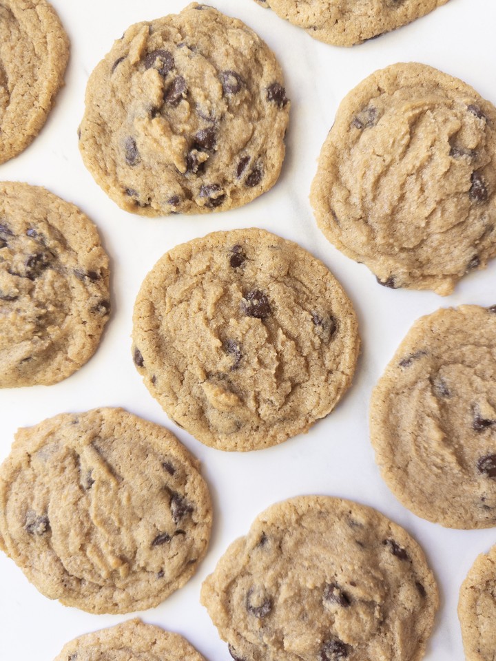 Overhead view of chocolate chip cookies made with a three-wheat blend, scattered on a marble surface