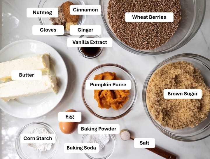 Labeled ingredients for chewy pumpkin cookies: wheat berries, cinnamon, nutmeg, cloves, ginger, vanilla extract, butter, pumpkin puree, brown sugar, egg, baking powder, corn starch, baking soda, and salt.