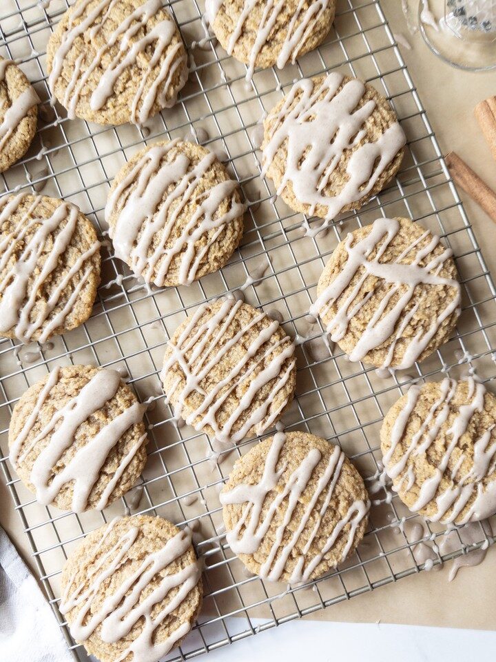 Chewy pumpkin cookies drizzled with brown butter icing, cooling on a wire rack.