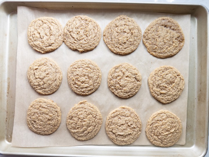 Baked pumpkin cookies resting on the baking sheet to finish setting before cooling.
