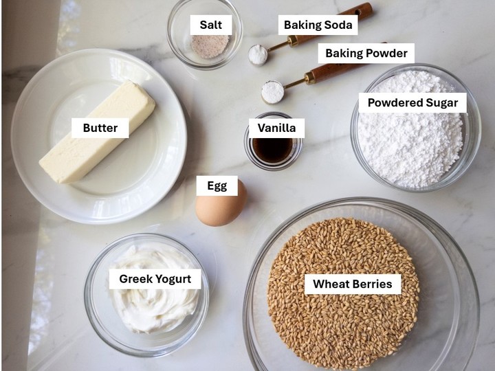 Labeled ingredients for soft frosted sugar cookies: wheat berries, butter, powdered sugar, egg, Greek yogurt, vanilla, salt, baking soda, and baking powder.